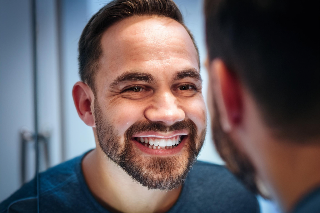 hombre mirandose al espejo con los dientes blancos