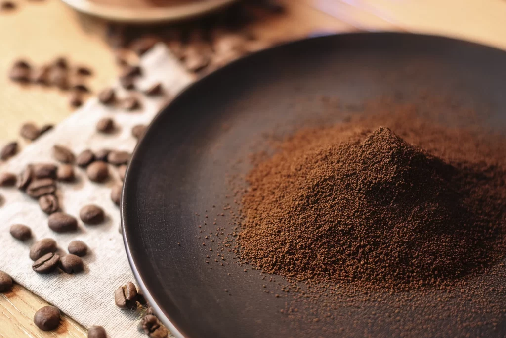 Granos molidos de café sobre un plato oscuro